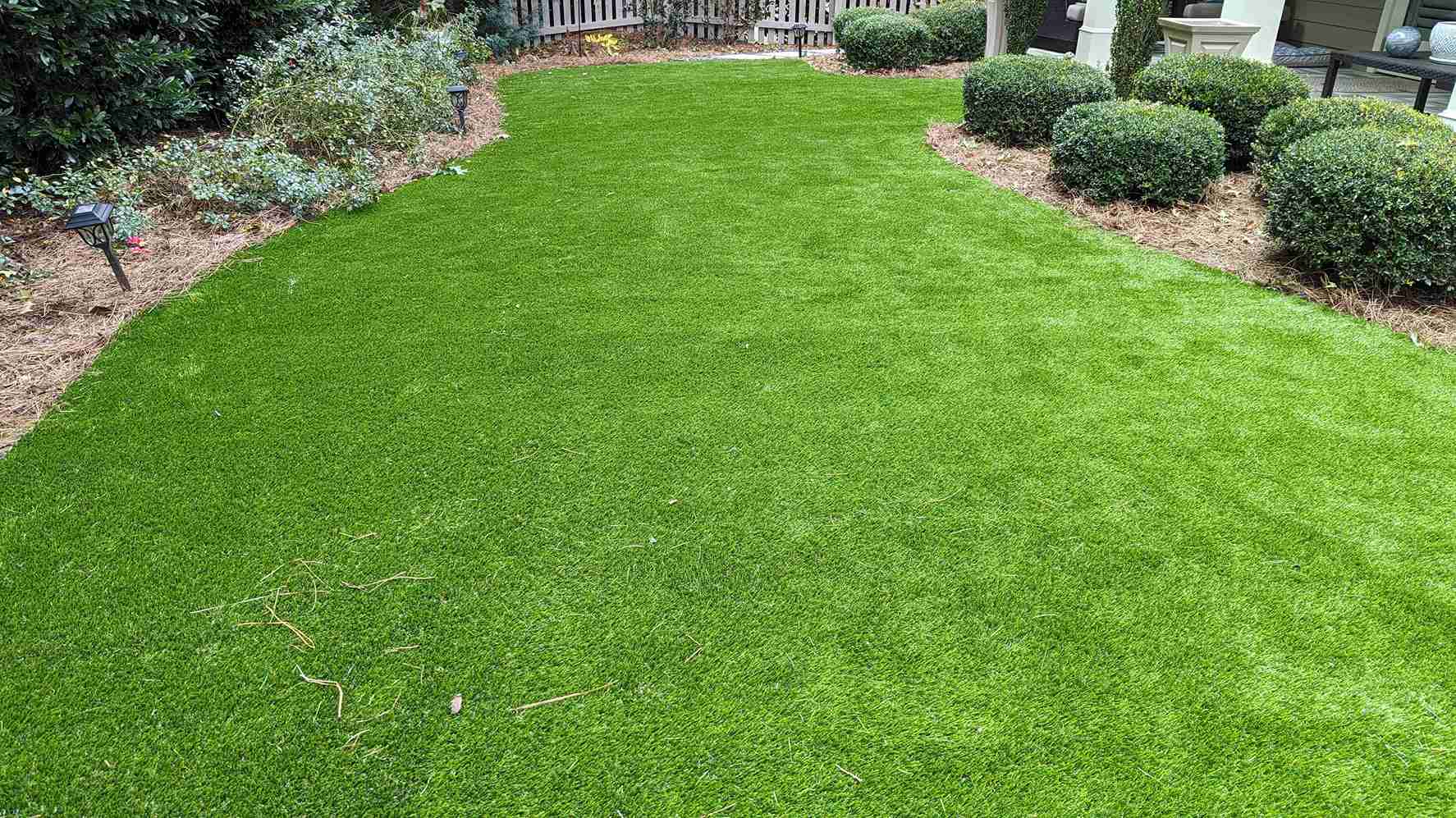 Manicured lawn edged with sculpted boxwoods and clean pine-straw borders
