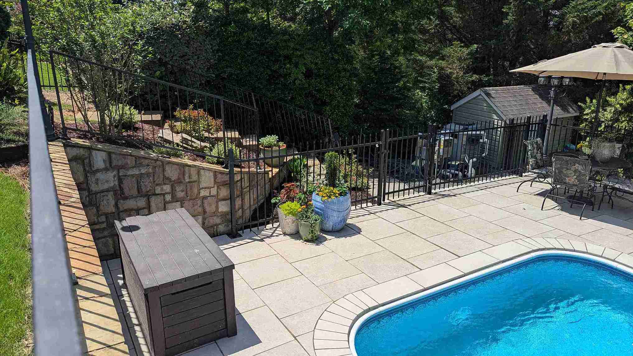 Pool patio with large-format pavers, a stone retaining wall and shaded seating